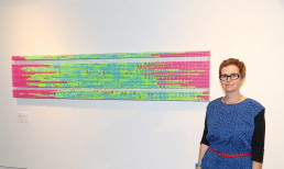 Linda Simon neben ihrem Kunstwerk Sleep Pattern aus verschiedenfarbigen uvex Gehörschutz-Ohrstöpseln
