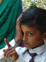 Kind in Nepal hält sich mit der Hand das rechte Auge zu.
