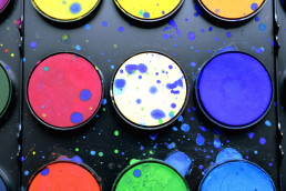 Malkasten mit bunten Wasserfarben und Farbspritzern