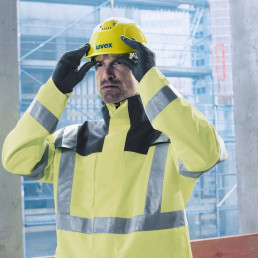 Bauarbeiter mit uvex Schutzhelm, Schutzhandschuhen und Schutzjacke in signalgelb mit Reflektorstreifen für bessere Sichtbarkeit