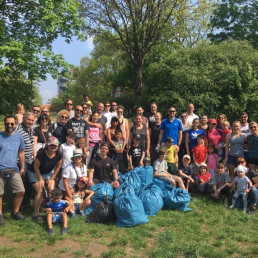 Plogger-Gruppe aus Frauen, Männern und Kindern posiert mit vollen Abfallsäcken für Gruppenfoto