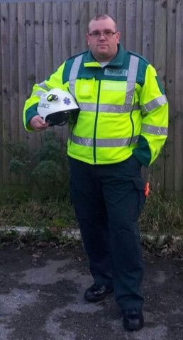 Sanitäter Scot Grant aus Sussex, England, in Berufskleidung: Warnjacke mit Reflektorstreifen und Schutzhelm