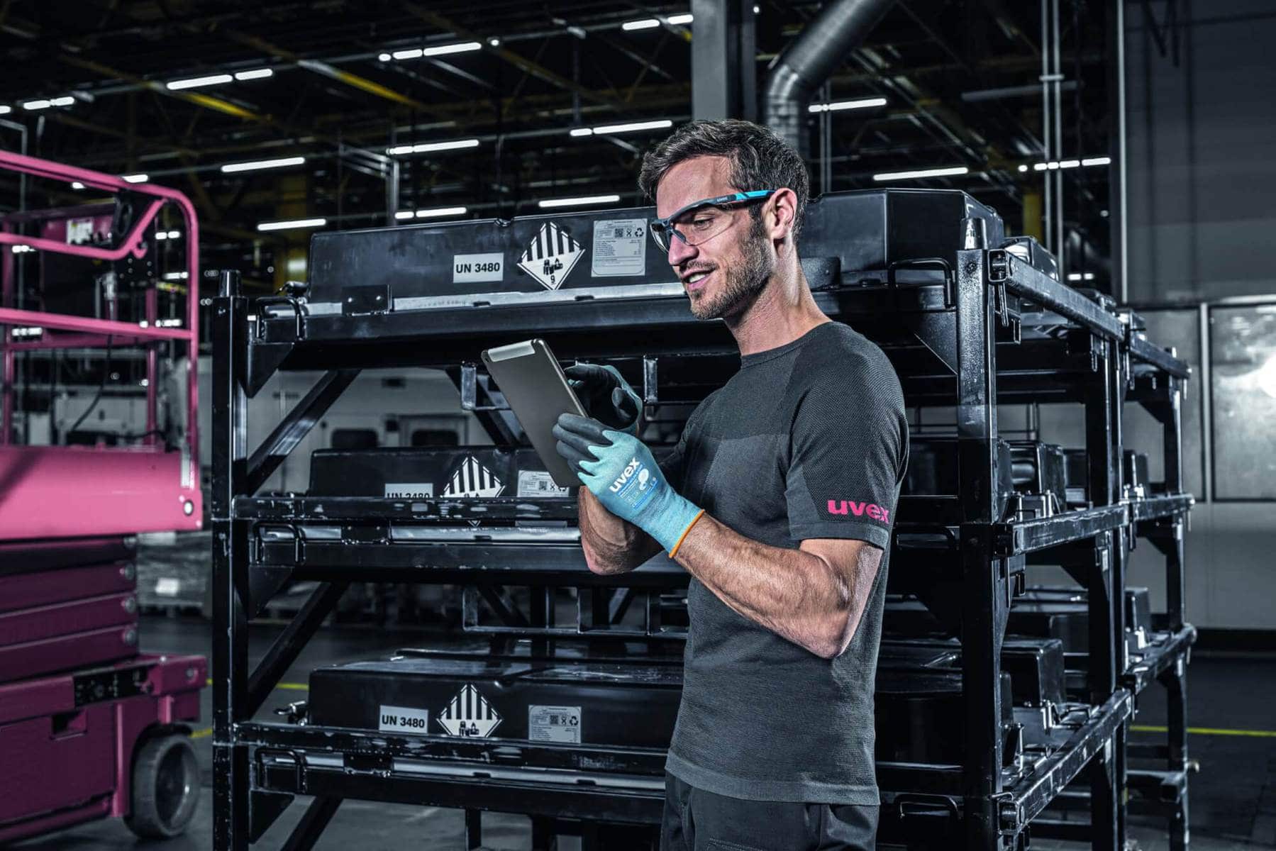 Industriearbeiter mit touchscreenfähigen uvex phynomic airLite Schutzhandschuhen bei der Bedienung eines Tablets