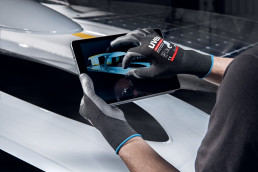 Ein Industriemitarbeiter bedient mit uvex phynomic airLite ESD-Schutzhandschuhen ein Tablet.