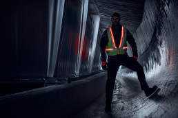Arbeiter mit selbstleuchtender Warnweste uvex protection active flash in einem dunklen Tunnel