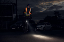 Radfahrer mit selbstleuchender Warnweste uvex protection active flash nachts im Straßenverkehr