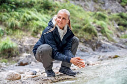 Frau in Outdoorkleidung aus der uvex alldayactive Kollektion mit innovativem Layering-System: robuste Outdoorhose, wärmende Outdoorjacke und wasserabweisender Funktionsjacke