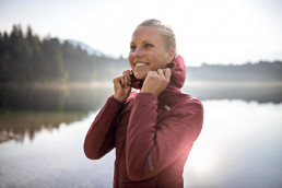 Frau mit isolierender und wärmender Outdoorjacke in rot aus der uvex alldayactive Kollektion