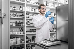 Apotheker mit uvex Schutzkleidung, Schutzhandschuhen und Schutzbrille für Laborarbeit in der Pharmaindustrie und Apotheken
