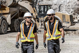 Zwei Bauarbeiter mit Warnwesten, Schutzkleidung, Schutzhandschuhen, Schutzbrillen und Schutzhelmen von uvex