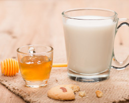 Große Tasse mit Milch und kleine Tasse mit Honig