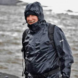 Mann mit waserdichter uvex Regenjacke und griffsicheren uvex Schutzhandschuhen beim Fliegenfischen in Alaska