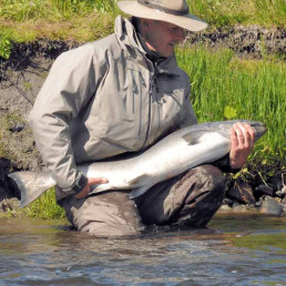 Mann in wasserfester Kleidung mit gefangenem Fisch in Alaska