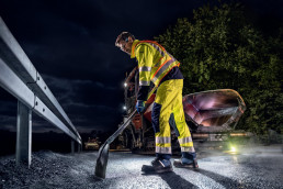 Arbeiter mit uvex 3 asphalt pro Sicherheitsschuhen nachts beim Asphaltieren einer Straße