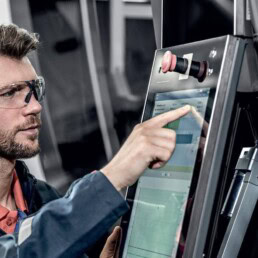 Arbeiter mit uvex Schutzbrille bedient Touchscreen