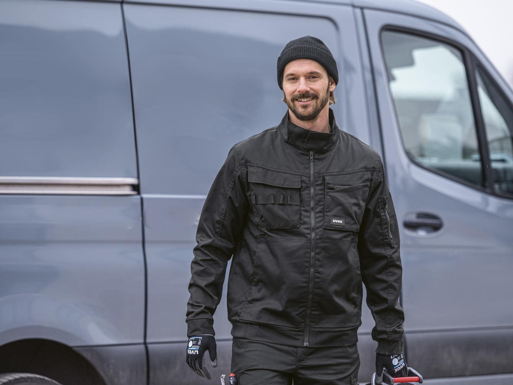 Ein Handwerker geht vor seinem Transporter